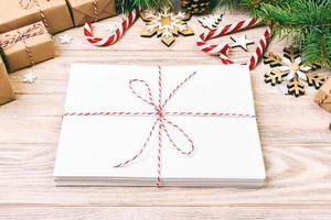 Envelope with blank sheet of paper on Christmas background - fir branch, pine cones, red ribbon, star and heart of sweets. Space for your text. Toned photo