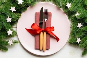 Top view of cutlery and plate on festive wooden background. New Year family dinner concept. Fir tree and Christmas decorations photo