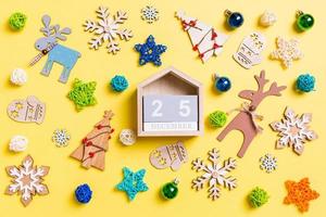 Top view of wooden calendar on yellow background with New Year toys and decorations. The twenty fifth of December. Christmas time concept photo