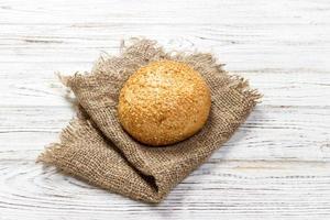 Fresh baked bread or bun with sesame and sunflower seeds on wooden table photo