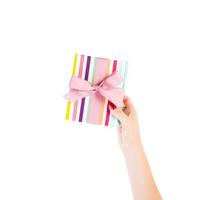 Woman hands give wrapped Christmas or other holiday handmade present in colored paper with pink ribbon. Isolated on white background, top view. thanksgiving Gift box concept photo