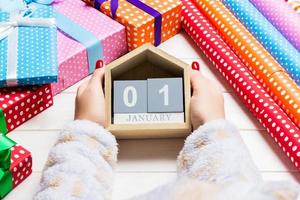 Top view of female hands holding a calendar on wooden background. The first of January. Holiday decorations. New Year concept photo