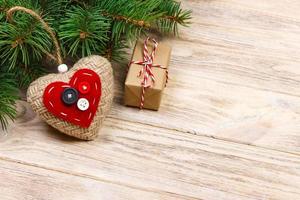 Christmas tree branch with red gift box and red hearts on wooden table. Top view with copy space photo
