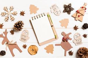 Top view of notebook on wooden background made of Christmas decorations. New Year concept photo