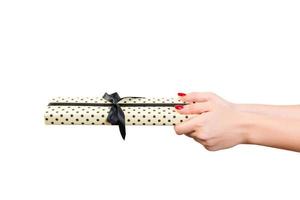 Woman hands give wrapped Christmas or other holiday handmade present in yellow paper with black ribbon. Isolated on white background, top view. thanksgiving Gift box concept photo