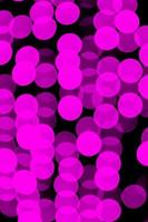 Unfocused abstract violet bokeh on black background. defocused and blurred many round light photo