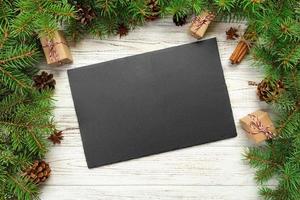 vista superior. placa rectangular de pizarra negra vacía sobre fondo de Navidad de madera. concepto de plato de cena navideña con decoración de año nuevo foto