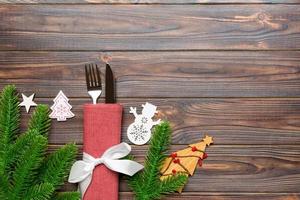 Top view of fork and knife on napkin with christmas decorations and new year tree on wooden background. Holiday and festive concept with copy space photo