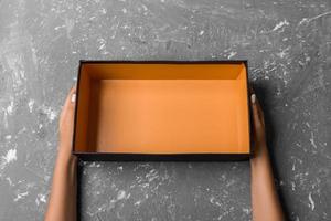 Female hands with open empty box on gray background photo