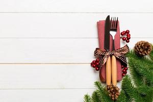 Top view of christmas decorations on wooden background. Fork and knife on napkin tied up with ribbon and empty space for your design. New year pattern concept photo