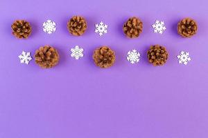 Top view of holiday composition made of pine cones and white snowflakes on colorful background. Winter time and Christmas concept with copy space photo