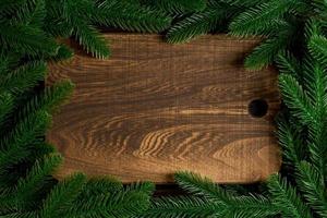 Top view of wooden plate decorated with fir tree branches. New Year dinner concept with empty space for your design photo