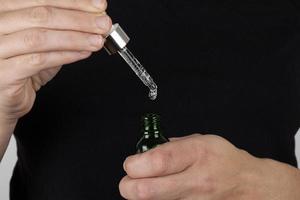 hand holds a pipette and a bottle of medicine in his hands photo