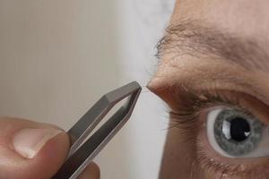 woman plucking eyebrow hairs with tweezers photo