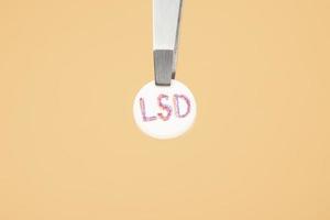 lsd medical tablet closeup, lysergic acid pill psychedelic drug on yellow background photo