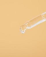 pipette with a drop of oil on a yellow background photo