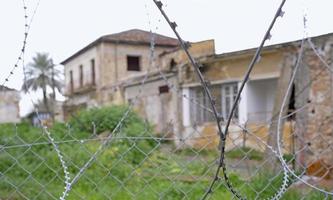 Nicosia, Cyprus, 2020 - Barbed wire at the border zone Green Line in Nicosia, Cyprus, with abandoned buildings in the background. photo