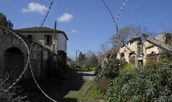 Nicosia, Cyprus, 2020 - Barbed wire at the border zone Green Line in Nicosia, Cyprus, with abandoned buildings in the background. photo