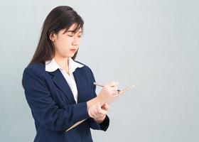 Asian woman long hair and wearing suit  with clipboard and pen in hands photo