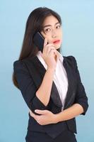 Women in suit holding smartphone against blue background photo