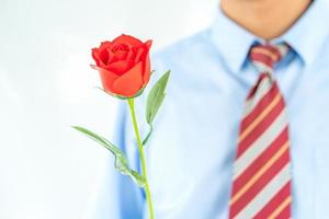 Man holding red rose in hand on white photo