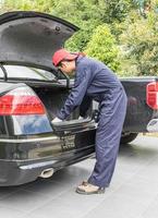 Mecánico reemplazando el neumático de repuesto en la parte trasera del coche. foto