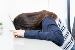 Young woman long hair fall asleep on desk with laptop photo