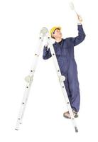 Handyman in uniform standing on ladder while using paint roller with clipping path photo