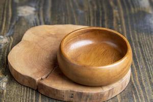 Wooden bowl on wooden table, empty round bowl for groceries and food photo