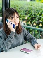 woman sitting and using smartphone for online shopping with credit card and passport on deck in home office photo