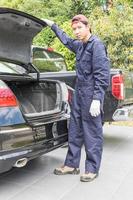 Mechanic replacing to the spare tire at the back of the car photo