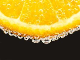 Close-up orange in sparkling water isolated black photo