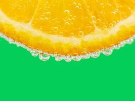 Close-up orange in sparkling water green background photo