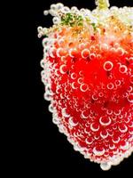 Close-up strawberry in sparkling water isolated black photo