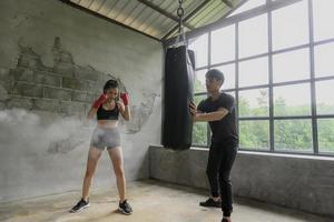 Asian male and female boxing trainers with sandbags in the gym. photo