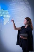 mujer empujando holograma de mapa mundial en pantalla virtual. concepto de tecnología de telecomunicaciones y negocios globales. foto