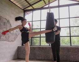 Asian male and female boxing trainers with sandbags in the gym. photo