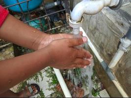 small child's hand washing hands using water flowing from the faucet photo