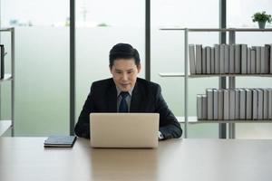 Online learning, Meeting, working and E learning concept. Casual Asian business man studying online course, meeting  via laptop computer in the office. photo