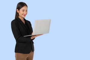 Young Asian working woman using Laptop computer isolated on light blue background. photo