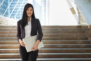 Young Asian woman sthanding and holding labtop computer  in the university, people education concept. photo