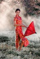 viajes, concepto de vacaciones en Japón, joven asiática con kimono japonés tradicional rojo y paraguas en el parque por la mañana. foto