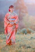 viajes, concepto de vacaciones en Japón, joven asiática con kimono japonés tradicional en el parque por la mañana. foto