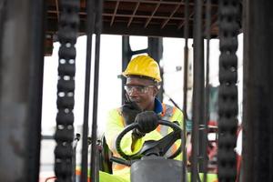 hombre trabajador conduciendo carretilla elevadora en almacén de contenedores industriales, hablando por walkie talkie. foto