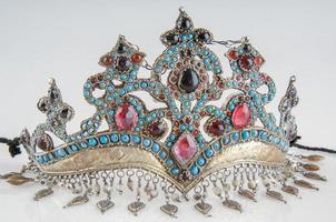 una tiara elegante y antigua con piedras preciosas y coloridas aisladas en un fondo blanco, primer plano foto