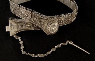 An antique, silver belt isolated on a black background, close-up photo