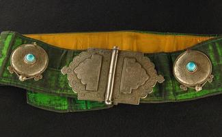 A Green, antique belt with precious stones isolated on a black background