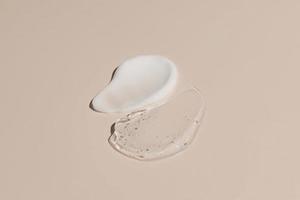 frotis de muestra de gel y crema de doble textura sobre fondo beige, suero de mucina de caracol transparente producto para el cuidado de la piel trazo plano, crema con ácido hialurónico foto