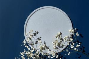 Concrete plate mock up, round dish on a blue background with flowers, concrete home decor, template for product placement, or food. top view photo