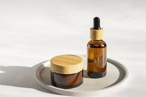 Set of empty cosmetic packaging, jar and bottle, mockup, on concrete round tray. Minimalism, still life, harsh shadows. photo